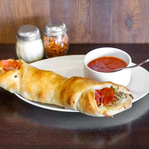 A golden-brown calzone filled with pepperoni and cheese, served with a side of marinara sauce.