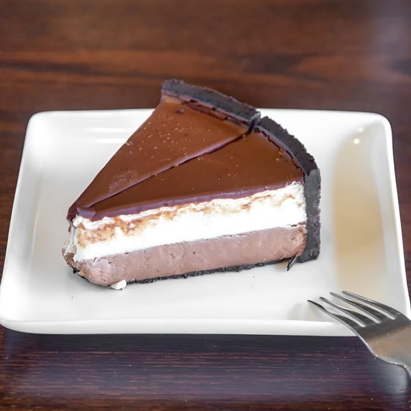 A slice of chocolate pie with three layers: chocolate crust, chocolate cream, and white cream.